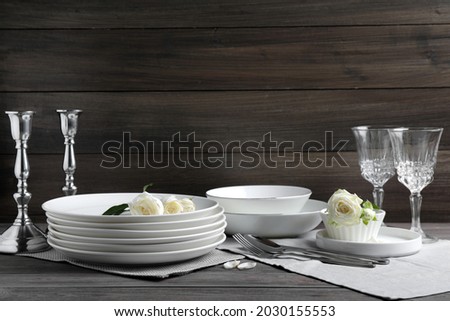 Set of clean dishware, cutlery and beautiful flowers on grey wooden table