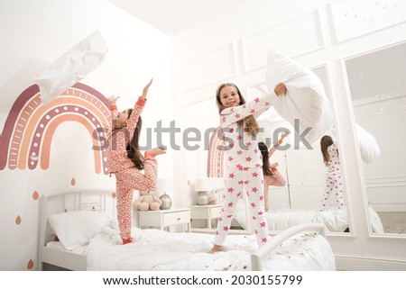 Cute little girls in pajamas playing on bed at home. Happy childhood Royalty-Free Stock Photo #2030155799