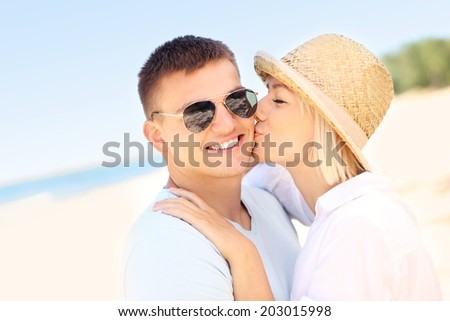 A picture of a woman kissing a man at the beach