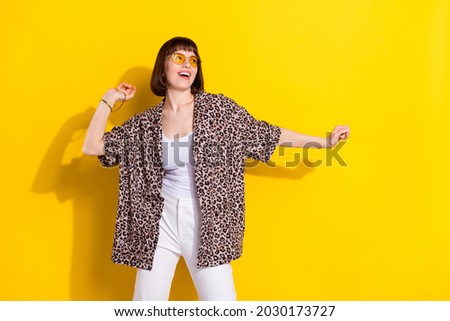 Photo of excited millennial lady dance look empty space wear eyewear accessories leopard shirt isolated on yellow color background