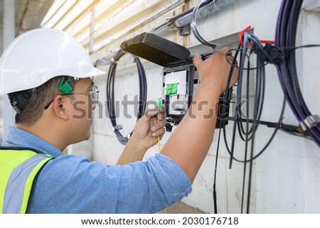 Engineer or technician checking fiber optic cables in internet splitter box.Fiber to the home equipment. FTTH internet fiber optics cables and cabinet. Royalty-Free Stock Photo #2030176718