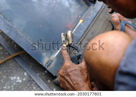 The worker is welding iron industrial steel background spark and light welding.