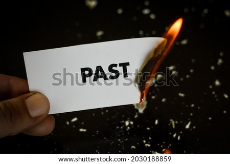 burning past, human hand holding the word past written on a paper burning with flame and ashes on a black background, concept