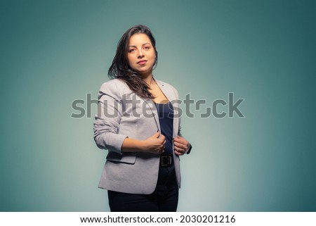 Business brunette woman adjusting her clothes on a blue background