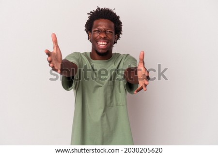 Young african american man isolated on white background  feels confident giving a hug to the camera.