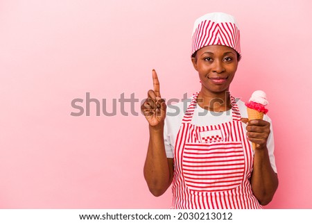 Young african american ice cream maker woman holding ice cream isolated on pink background showing number one with finger.