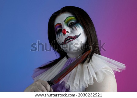 Latin woman with diabolical clown makeup, holding a knife in her hand, halloween theme