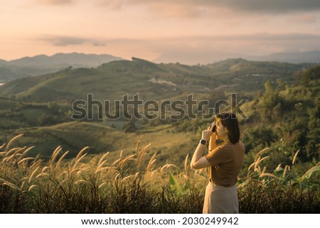 solo woman travel take photo and sightseeing sunrise on mountain at thailand
