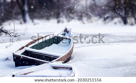 Snow-covered boat on the river in winter during a snowfall