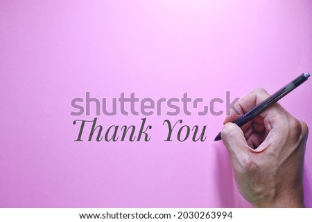 Thank You text words typography, Business Concept, Motivational concept. Marketing and Communications Concept. A man's hand writes thank you, High angle view. Pink Background