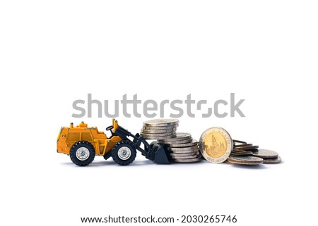 Plastic model of a tractor loader and a bunch and coin isolated on white background - Saving money concept