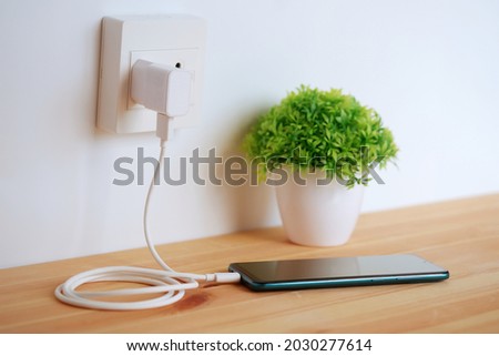 Plug in power outlet Adapter cord charger of smart phone on wooden floor Royalty-Free Stock Photo #2030277614