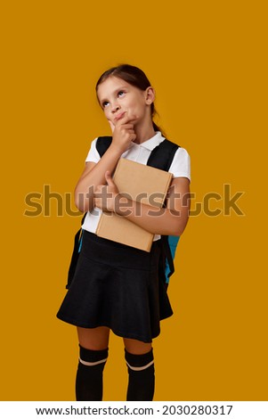 cute schoolgirl with backpack and book full length.