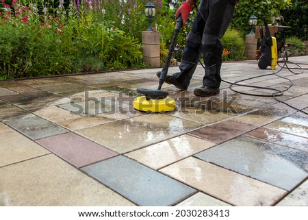Cleaning stone slabs on patio with the high-pressure cleaner. Person worker cleaning the outdoors floor.  
