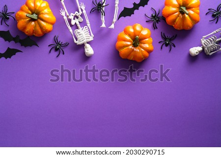 Happy Halloween party composition with pumpkins, skeletons, spiders, bats on violet background. Top view, flat lay.
