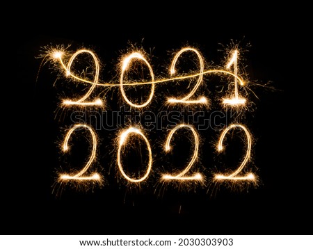 Happy New Year 2022. Sparkling burning text Happy New Year 2022 isolated on black background. Beautiful Glowing golden overlay object for design holiday greeting card