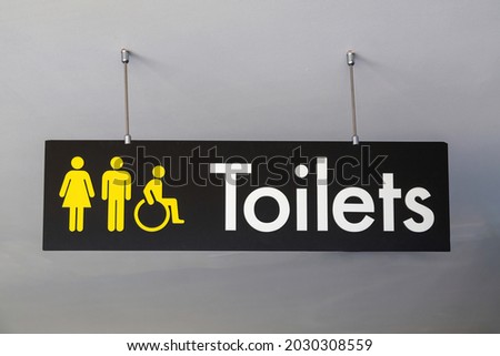 a toilets sign hanging from the ceiling pointing to the male female and disabled toilets