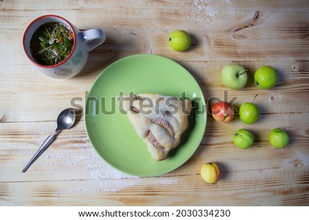 Piece of Apple pie on plate, cup of herbal tea, spoon on wooden background