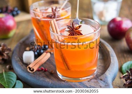 Autumn hot drink, spicy apple cider with apple slices in glasses on a wooden tray. American cuisine. Thanksgiving Day