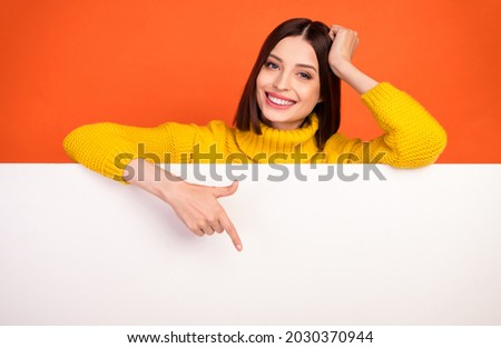 Photo of young woman happy positive smile point finger empty space poster ad promo choose isolated over orange color background