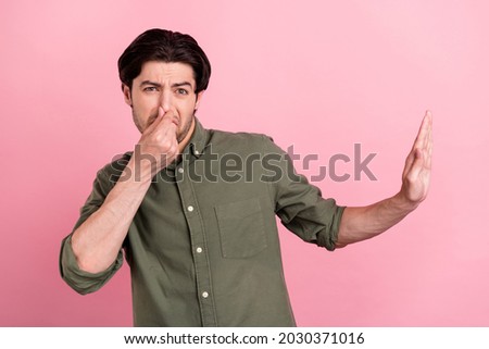 Photo of exhausted annoyed disgusted guy show stop gesture cover nose wear khaki shirt isolated pink color background Royalty-Free Stock Photo #2030371016