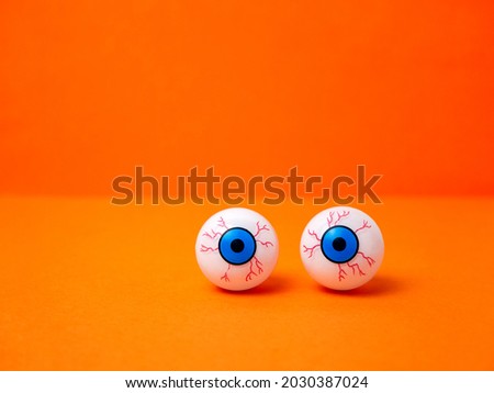 Scary and funny eyes on an orange background for Halloween, copy space