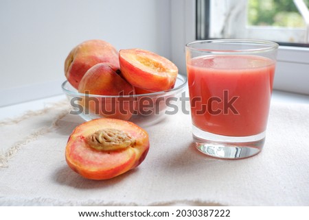 Smoothie made of ripe peaches and watermelon. Healthy food, proper nutrition. Breakfast, snack. In the photo, a glass glass with smoothies and peaches on a light fabric.