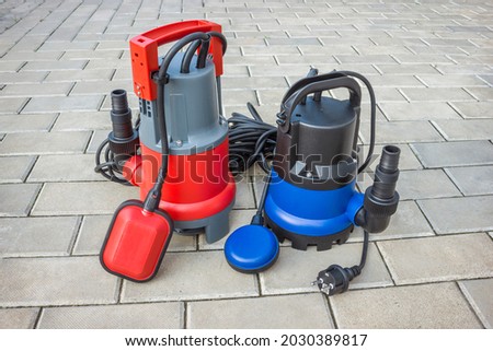 Two household submersible pump with plastic housings  on stone floor of courtyard Royalty-Free Stock Photo #2030389817