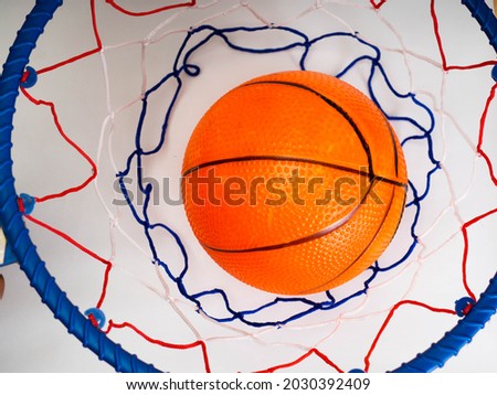 Picture of an orange basket ball on a basket ring. Shoot on a white background