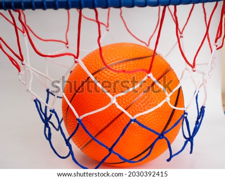 Picture of an orange basket ball on a basket ring. Shoot on a white background