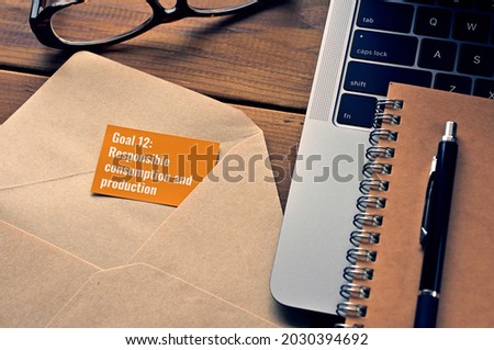 There is a card with the word of Goal 12:Responsible consumption and production which is one of the goals of the Sustainable Development Goals.It's by the envelope or laptop computer.
