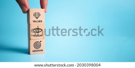 Mission vision values concept icon on wooden cubes stacked vertically on beautiful blue background. Copy space. Used for banner to communicate organization to identify business policy and direction. Royalty-Free Stock Photo #2030398004