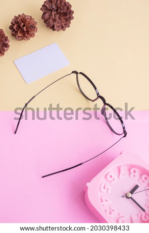 Stylish glasses over pastel background. Business Card, Pastel Pink And Yellow Colors. Alarm Clock, Fir Tree Flowers.
