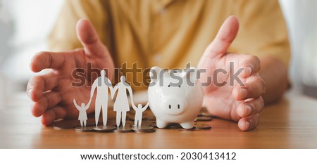 Businessman take a position to protect on the piggybank and paper family in hand, donation, saving, charity, family finance plan concept, fundraising, superannuation, financial crisis concept Royalty-Free Stock Photo #2030413412