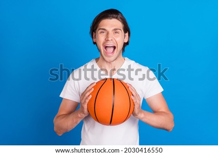 Photo portrait brunet man keeping ball shouting loud in white t-shirt isolated vivid blue color background