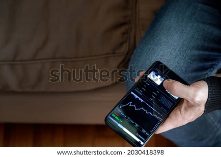 Close-up of man's hand consulting a finance app on his mobile phone