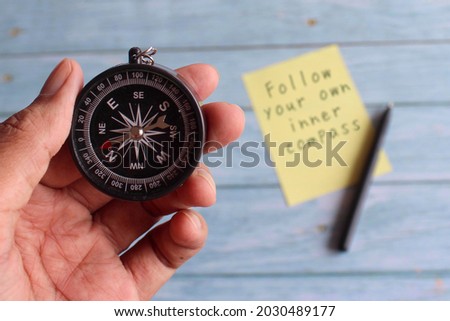 Motivational life quotes. Selective focus image of hand holding compass and text FOLLOW YOUR OWN INNER COMPASS Royalty-Free Stock Photo #2030489177