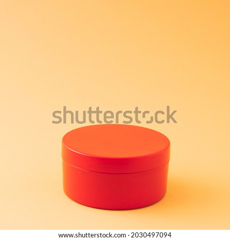 Red round gift box on ocher and orange background with copy space. Advertisement idea. Minimal banner ad concept.