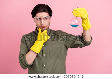 Photo of young minded man look hold hand chemical chin wear rubber gloves isolated on pastel pink color background