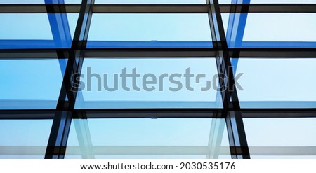 Sky visible through glass wall, ceiling or roof. Minimalist architecture of modern building. Abstract background on construction industry or technology with geometric pattern of parallel lines.