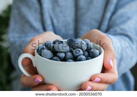Woman holding bowl with Frozen blueberry fruits. Harvesting concept. Female hands collecting berries. Healthy eating concept. Stocking up berries for winter Vegetarian vegan food. Dieting nutrition Royalty-Free Stock Photo #2030536070