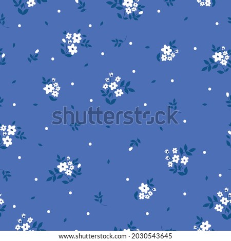 Seamless vintage pattern. small white flowers and dots, blue leaves on a bright blue background. vector texture. trend print for textiles and wallpaper.