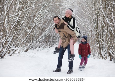 Young family with children are walking in the winter park. Winter walk of parents with children. Walking on holiday weekend in the winter.
