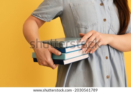 Woman with stack of books on color background
