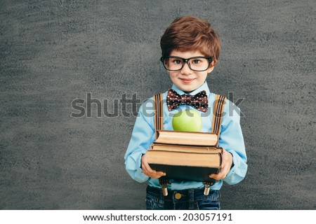 Cheerful smiling little kid (boy) against chalkboard. Looking at camera. School concept