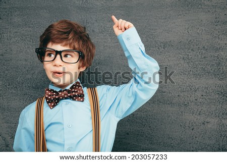 Cheerful smiling little kid (boy) against chalkboard. Looking at camera. School concept