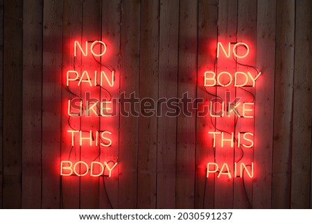 Neon sign on wooden wall red light NO PAIN