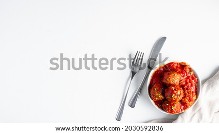 Top view of meatballs ball with tomato sauce and silver cutlery on whitebackground.Large iname for banner with copy space 