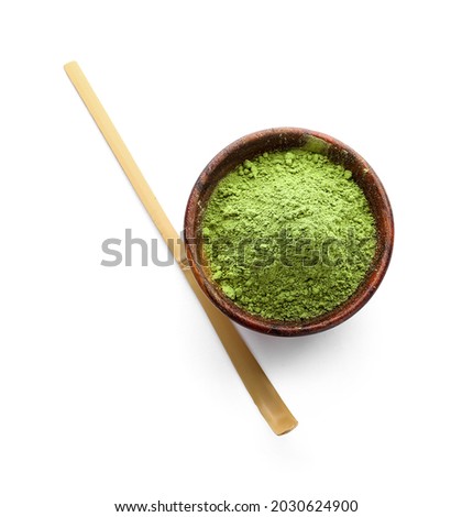 Bowl with powdered matcha tea and chashaku on white background