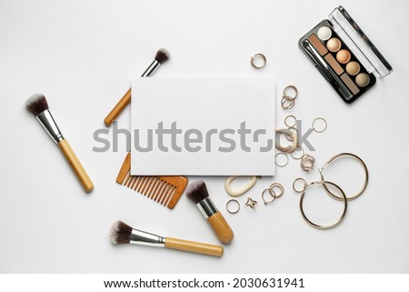 Composition with blank card, makeup cosmetics and female accessories on white background